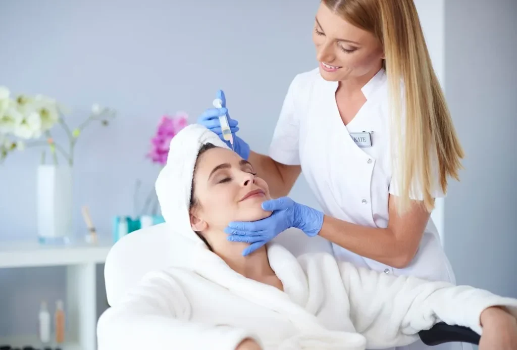 Woman receiving a skincare treatment from a professional in a medical spa, highlighting the benefits of aesthetic services like microneedling and laser treatments.