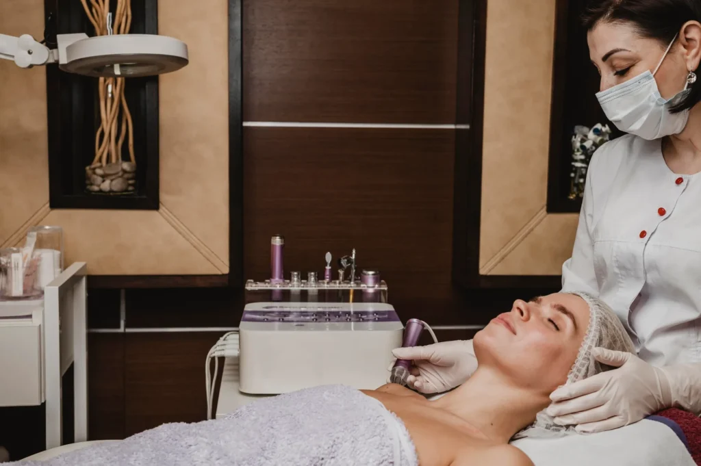 Woman receiving a facial treatment from a masked aesthetician in a MedSpa setting, highlighting skincare and rejuvenation services.
